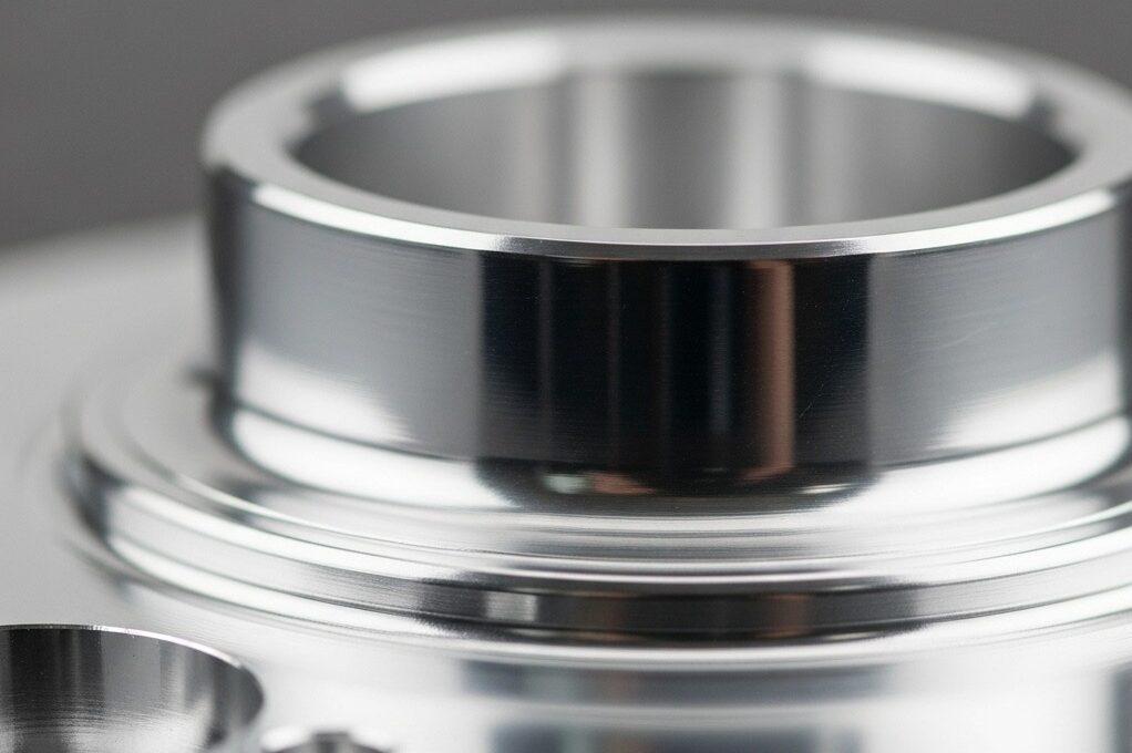 Una toma en primer plano y alta resolución en estudio de un componente de aluminio de alto brillo perfectamente mecanizado que refleja la luz brillantemente, mostrando su espejo 1 e1758788804333